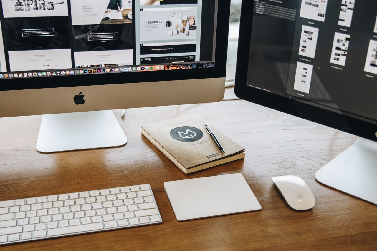 Un espace de travail épuré avec deux écrans, un clavier, une souris et un carnet, pensé pour la productivité.